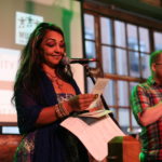 woman smiling and reading at mic