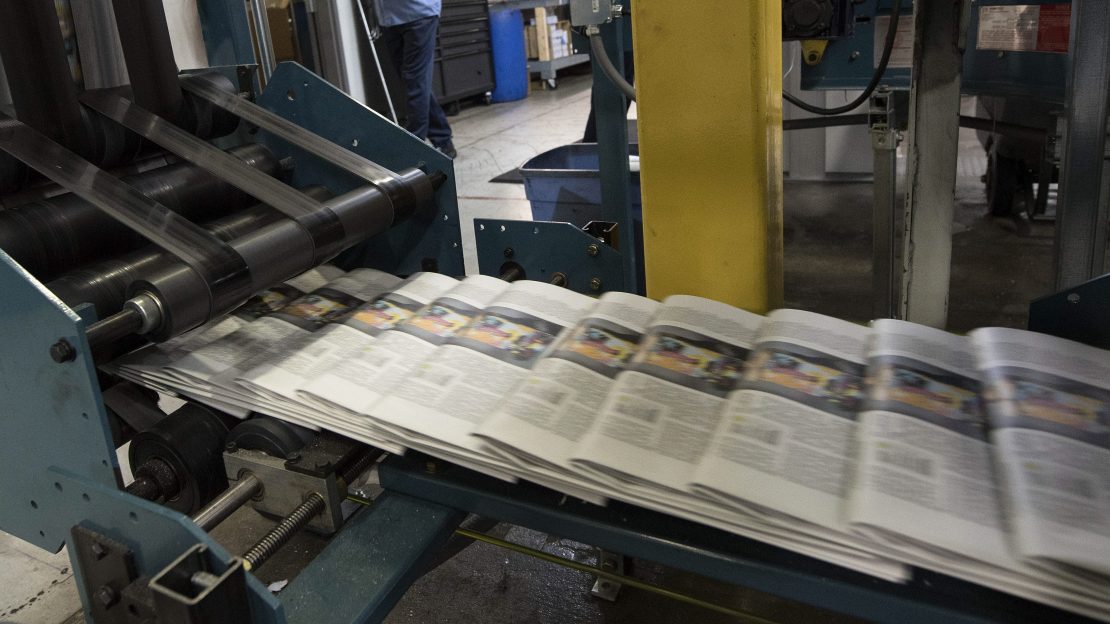 This picture shows newspapers coming out of a machine rapidly.