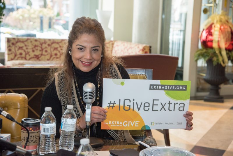 Woman smiles with Extra Give sign