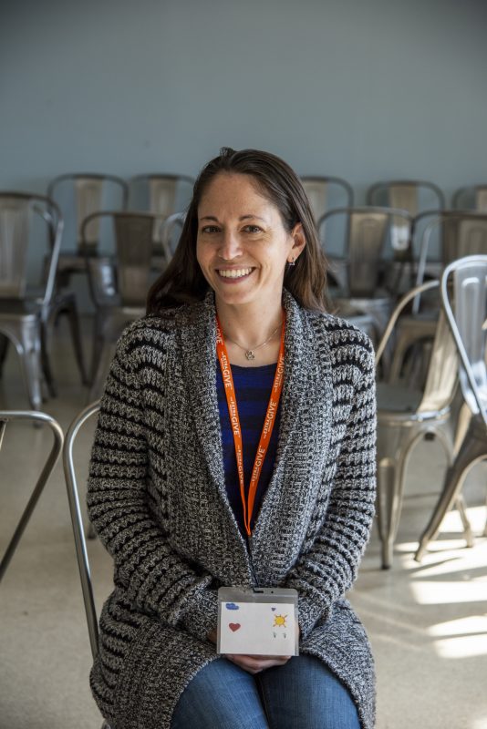 Woman smiles for camera, empty chairs are in the background
