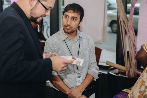 A man is reading a pamphlet while another man looks up at him.