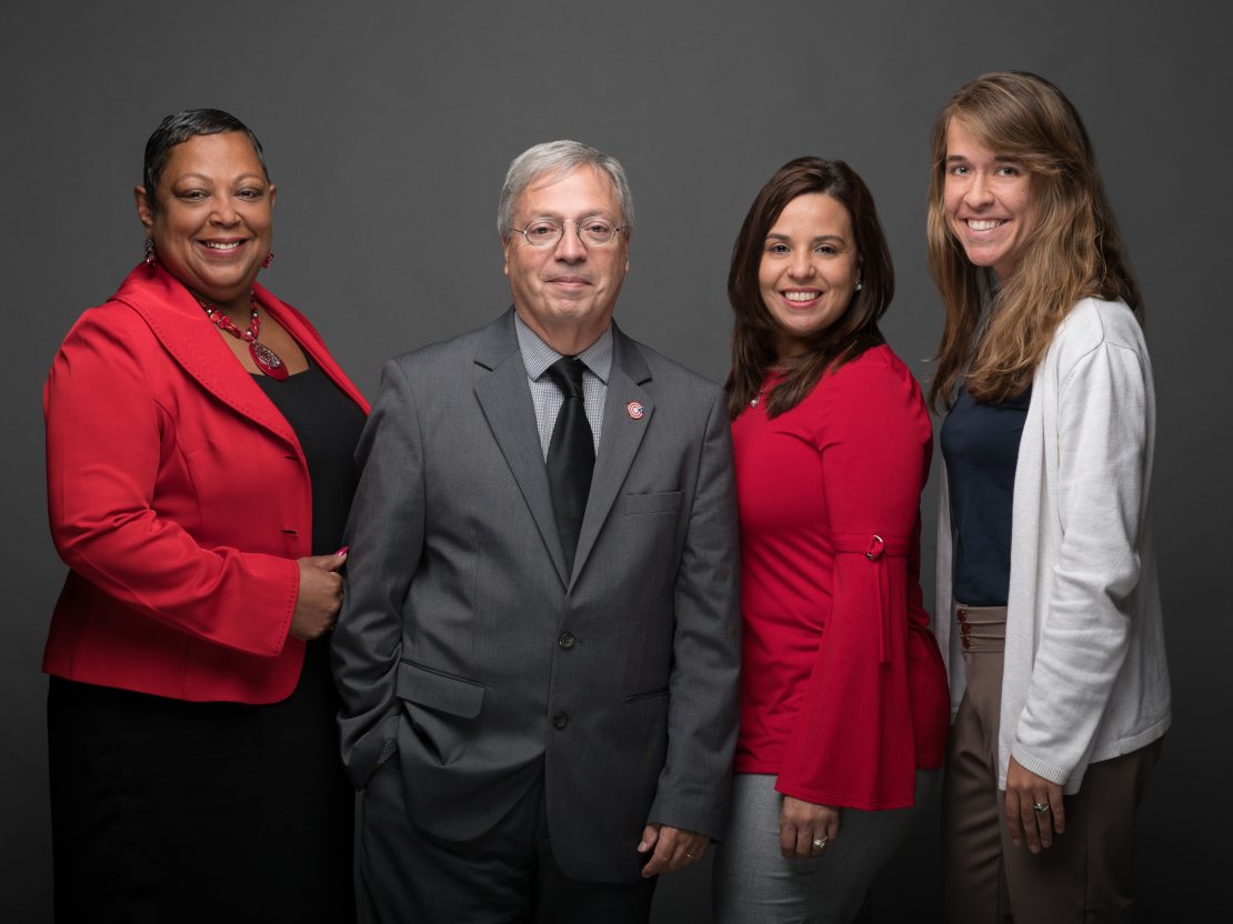 A group of people stand together smiling.