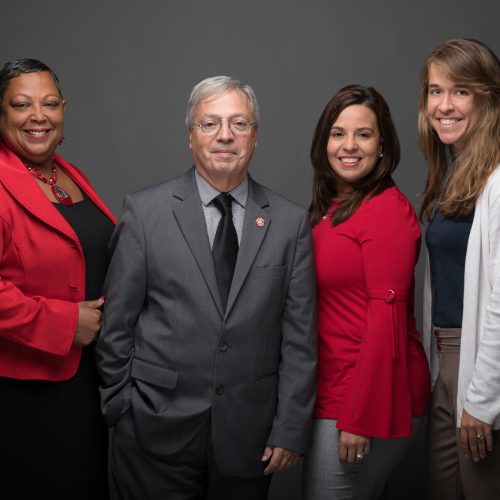 A group of people stand together smiling.