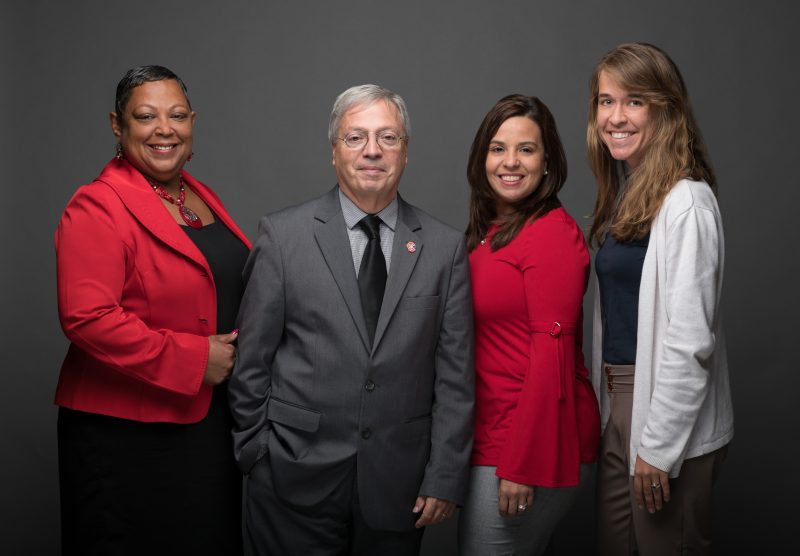 A group of people stand together smiling.