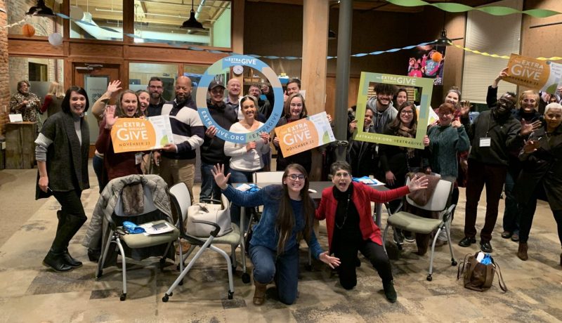 Photo of people gathered in a clump holding extra give signs.