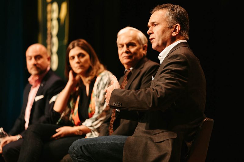 photo of four people sitting on stage with microphones