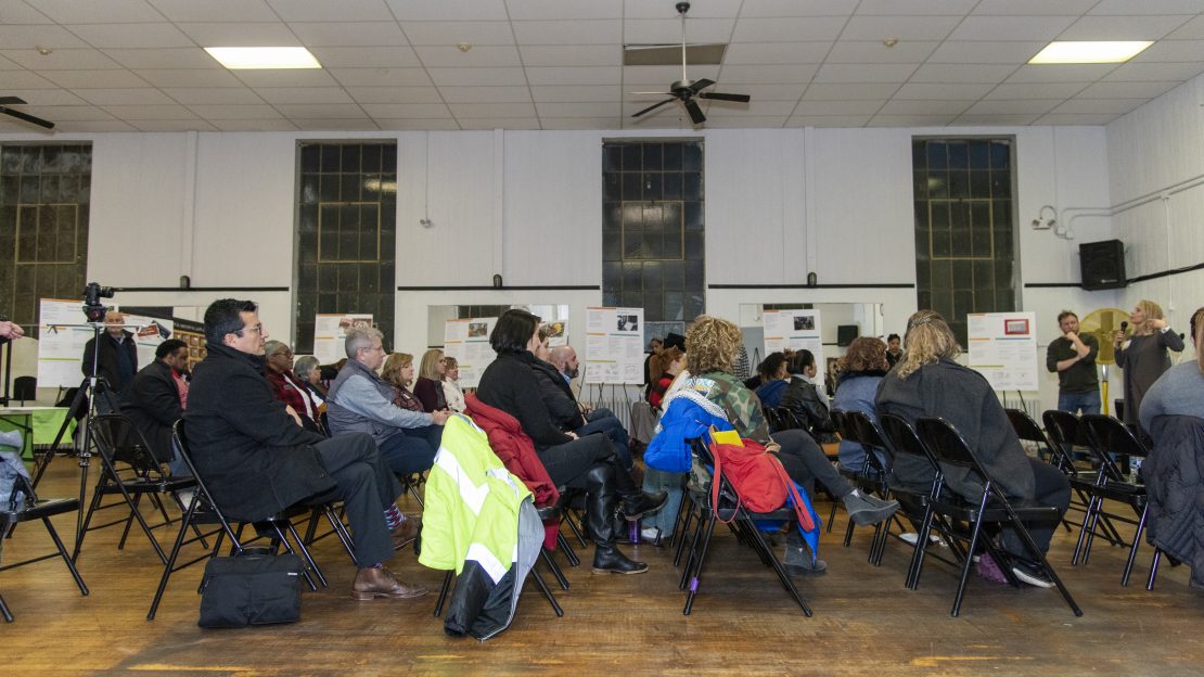 People sitting in rows of chairs facing two speakers