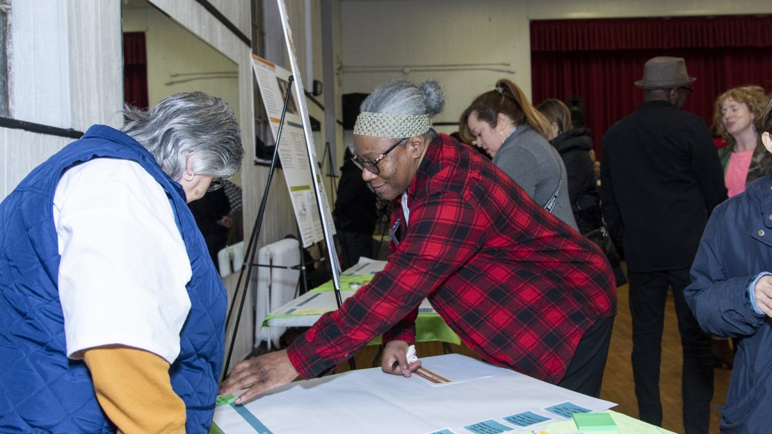 Group of people standing around poster boards and tables