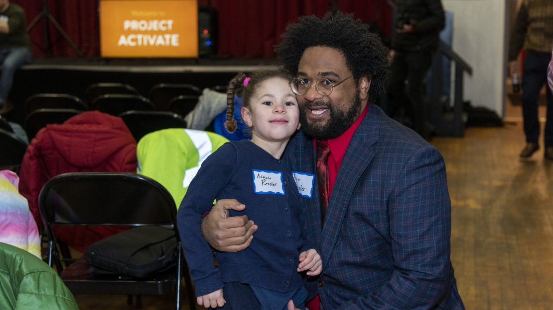 Man smiles with child sitting on his knee
