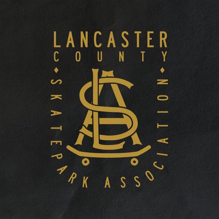 This picture shows the Lancaster County Skatepark Association logo, with the letters "L" "S" and "A" superimposed on top of each other and riding a skateboard
