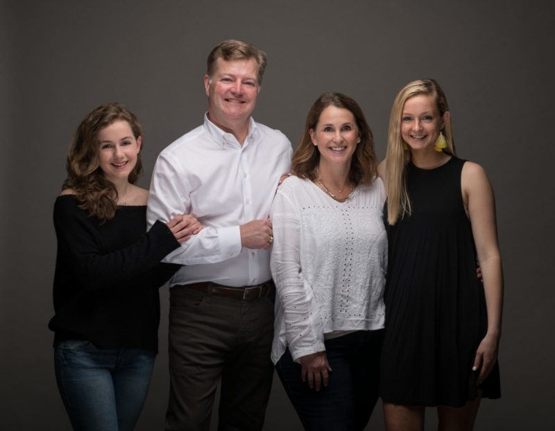 A family looks directly at the camera, smiling.