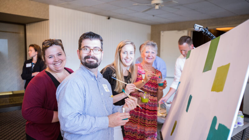 Group of people work on painting a poster board