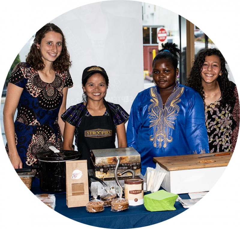 Four people smile, standing behind table with stroopie products