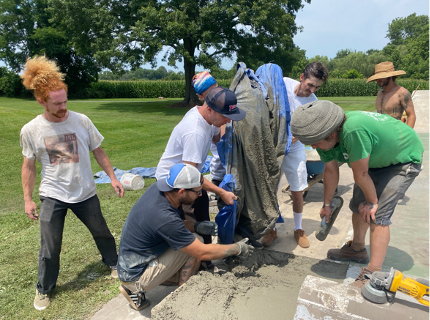 A picture of a group of people pouring concrete into the ground to create a skatepark