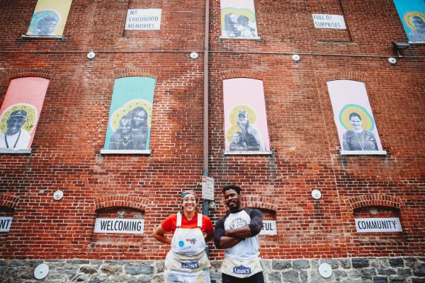Two artist stand in front of project