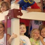 photo of young children smiling while sitting on a jungle gym