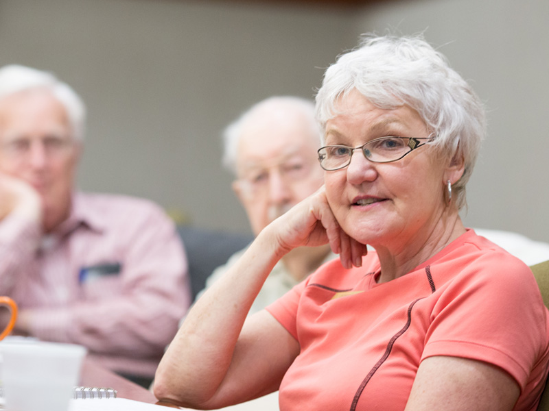 Woman smiling at camera, two men in the background.