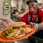 Woman hands plate of food over counter