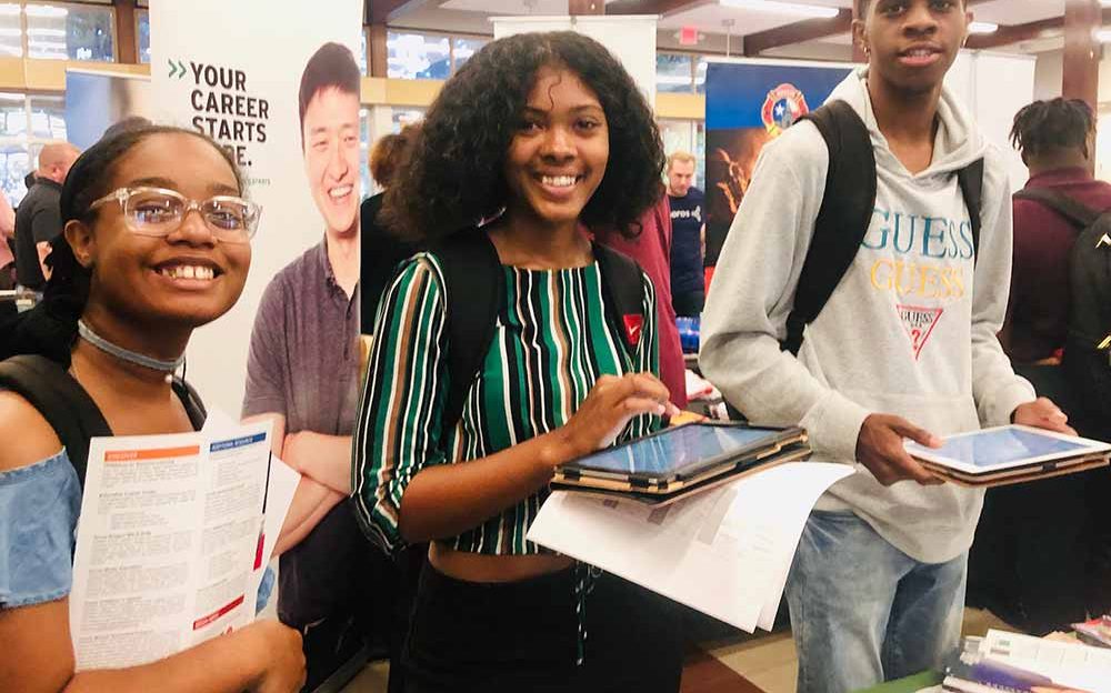 Three students smile at camera