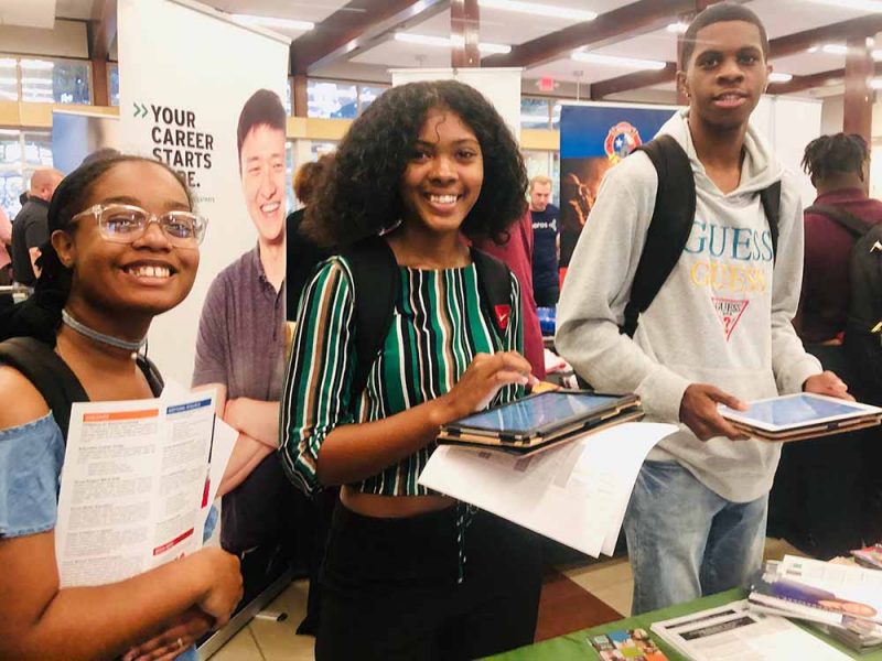 Three students smile at camera